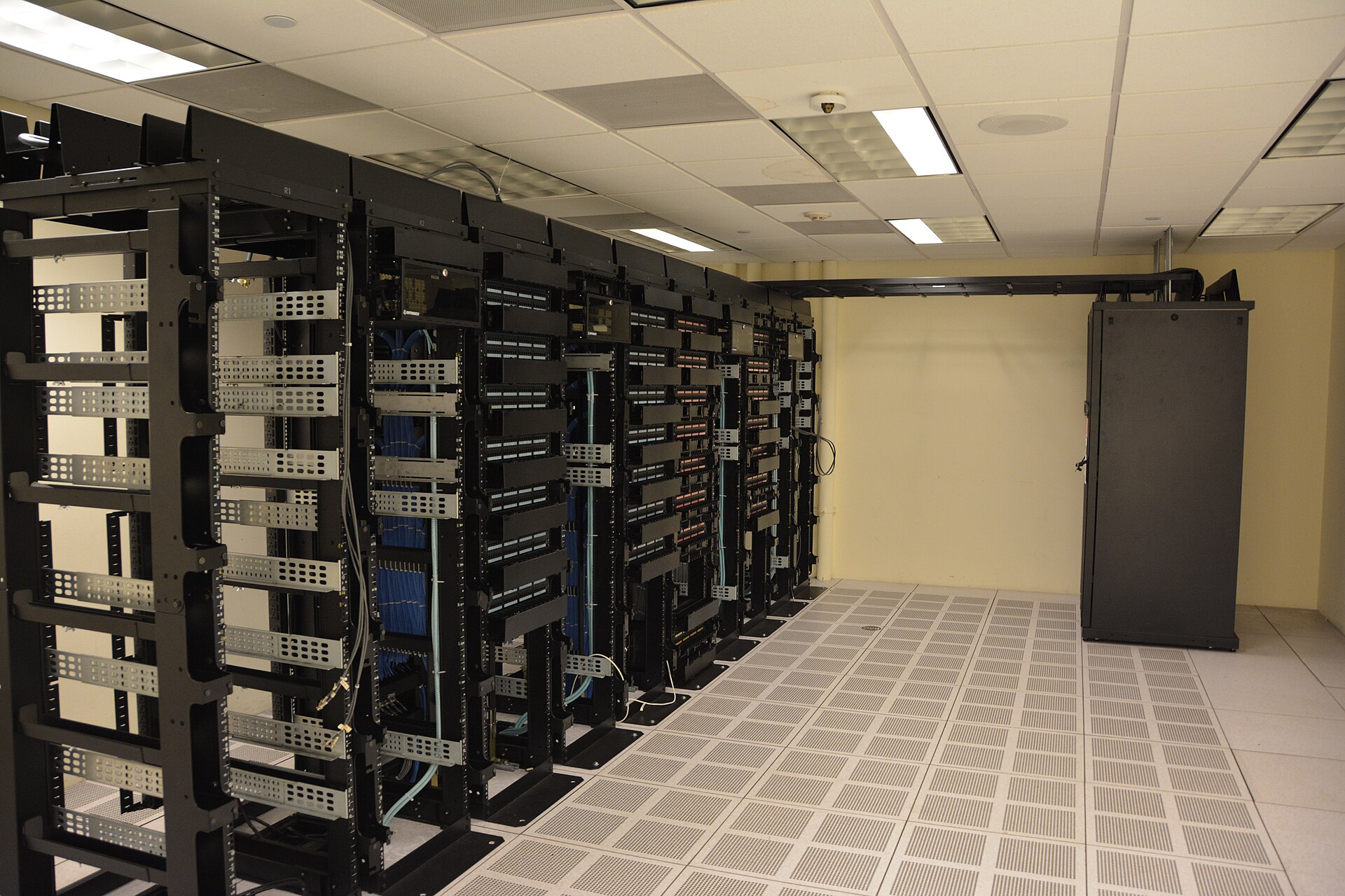 Pasillo de racks de un centro de datos, con cableado estructurado, suelo técnico perforado y bandeja portacables
